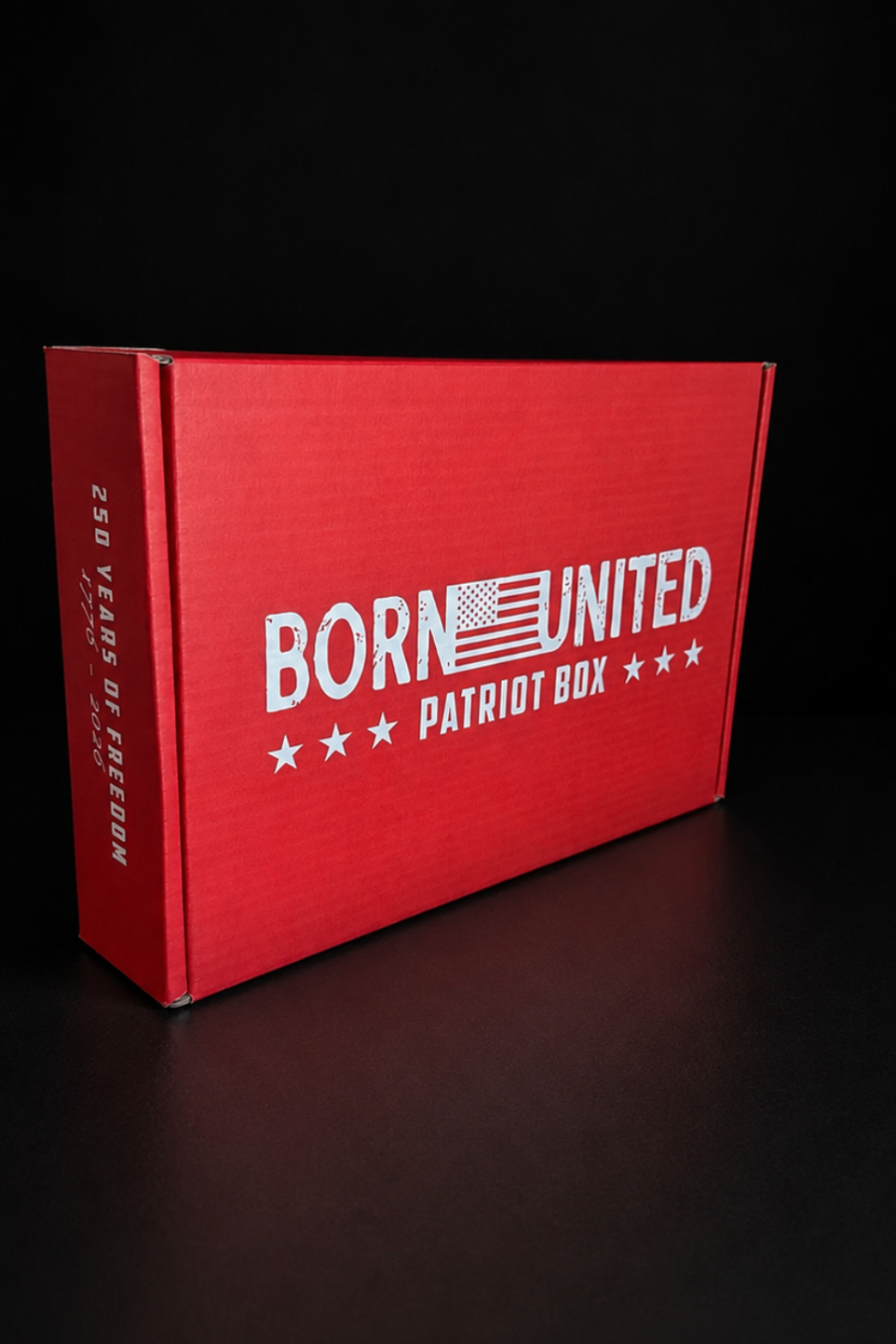 A red Born United Patriot Box by Born United Private Label features white "Born United Patriot Box" text and a stylized American flag. One side reads "250 Years of Freedom." Ideal for storing Limited Edition Tees or Challenge Coins against a black background.