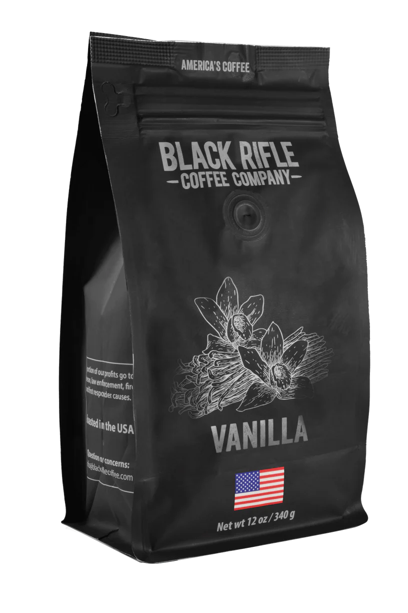 A 12 oz (340 g) bag of Black Rifle Coffees Vanilla Coffee-Ground features black packaging with vanilla flowers, the brands logo, and an American flag. It reads Americas Coffee, delivering a balanced taste typical of premium flavored coffees.