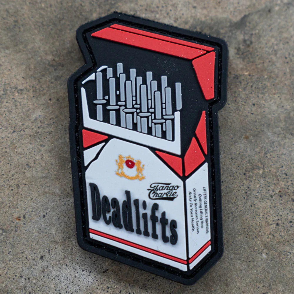 The Deadlift PVC Patch by Tango Charlie Apparel is shaped like a cigarette pack, but with barbells inside and Deadlifts boldly labeled on a concrete-style background.