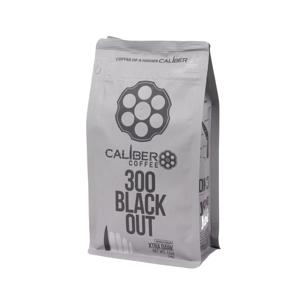 A silver coffee bag labeled Caliber Dark Roast 300 Blackout - Whole Bean by Caliber Coffee Company, features a revolver cylinder logo and bullet illustrations. Text reads Coffee of a Higher Caliber and Extra Dark Roast Net Wt. 12oz, highlighting its specialty-grade, single-origin excellence.