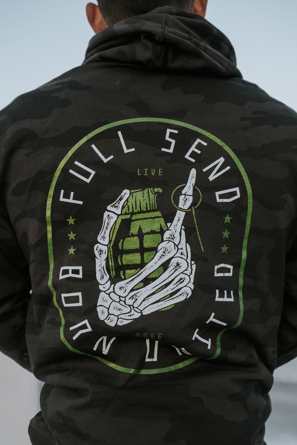 Wearing the Full Send Camo Hoodie by Born United Private Label, featuring a skeleton hand clutching a grenade with FULL SEND and BORN UNITED, embodies the bold Full Send spirit.