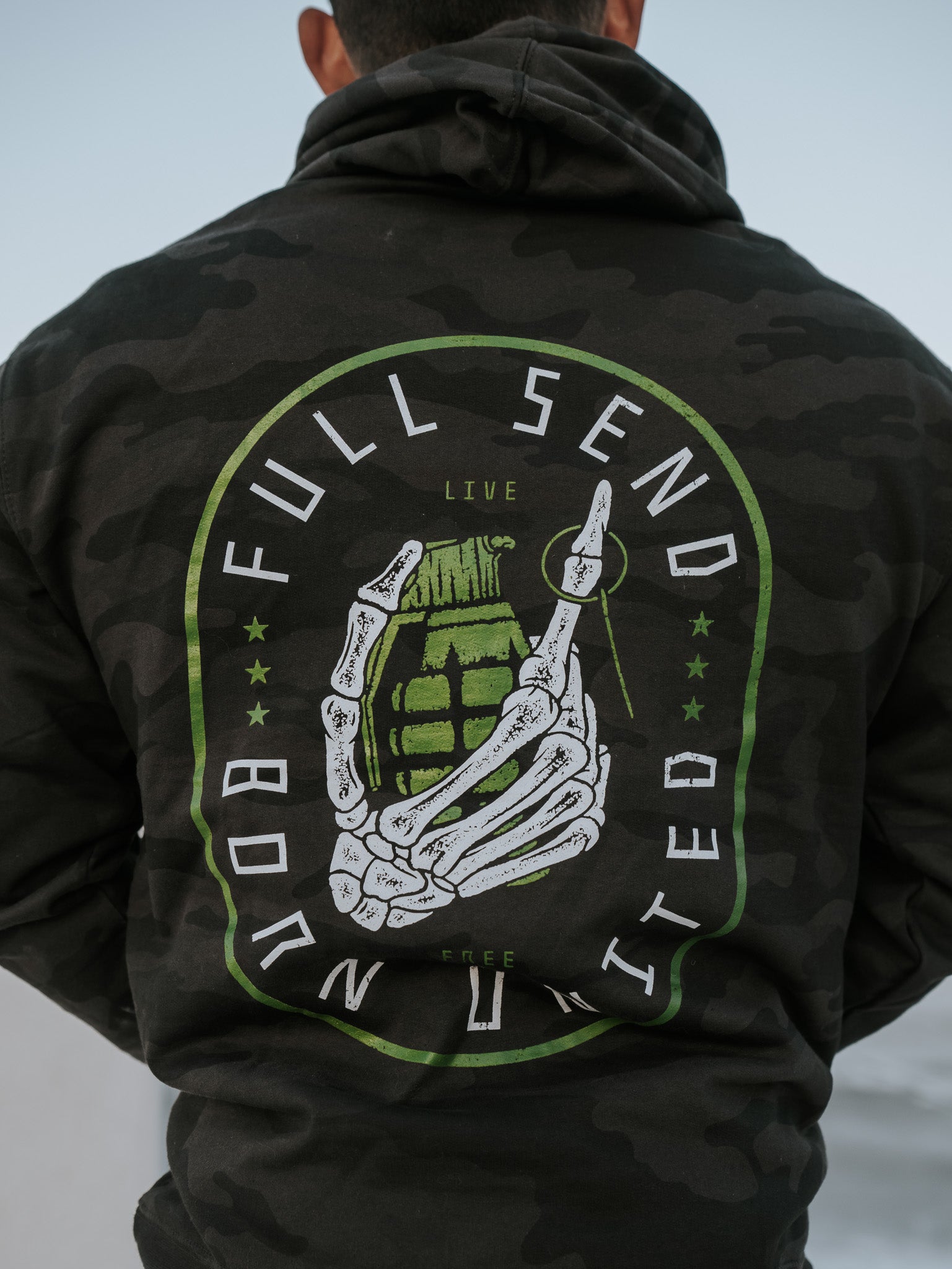 Wearing the Full Send Camo Hoodie by Born United Private Label, featuring a skeleton hand clutching a grenade with FULL SEND and BORN UNITED, embodies the bold Full Send spirit.