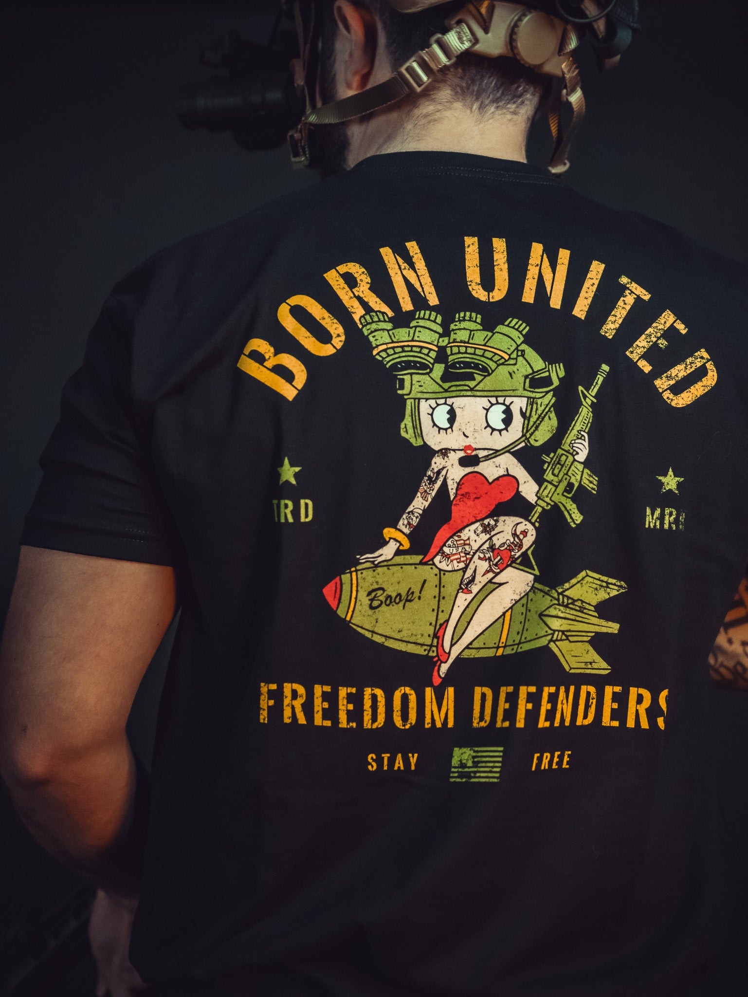 A person in a Born United Betty Boop Tee, featuring a cartoon character on a bomb, displays the phrases Born United, Freedom Defenders, and Stay Free, boldly conveying their commitment to defending freedom.