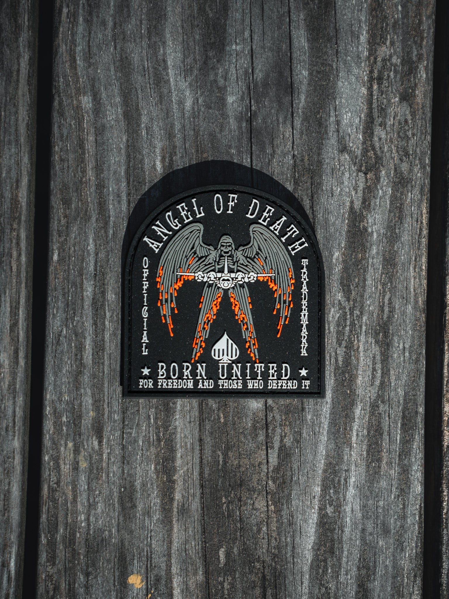 The Angel Of Death PVC Patch from Born United Private Label features a winged figure with flaming swords and the words Angel of Death and Born United for Freedom and Those Who Defend It, designed in black, white, and orange.