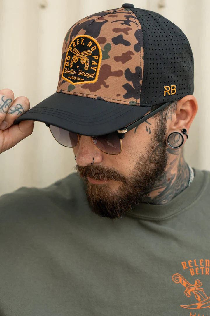 A tattooed man sports a Relentless Betrayal No Prey, No Pay Frog Camo Hat with an orange design and dark mesh sides, embodying a pirate lifestyle. He pairs it with sunglasses and a green tee showcasing bold orange writing while adjusting the cap.