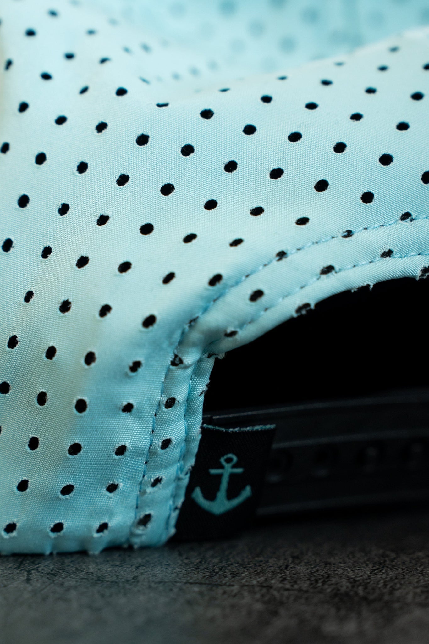 The Sink or Swim Seafoam PVC Snapback by Relentless Betrayal features a light blue polka-dotted design with a black adjustable strap and anchor symbol. Its water-resistant fabric ensures durability, and stitching details are prominent, making it perfect for the pirate lifestyle.