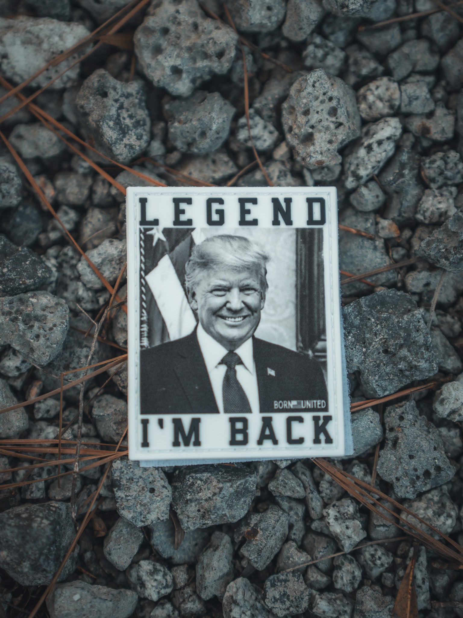 Born United Private Labels I’m Back Patch displays a black-and-white image of a suited man, surrounded by the text LEGEND IM BACK, on rocky terrain, evoking a presidential comeback akin to historic victories.