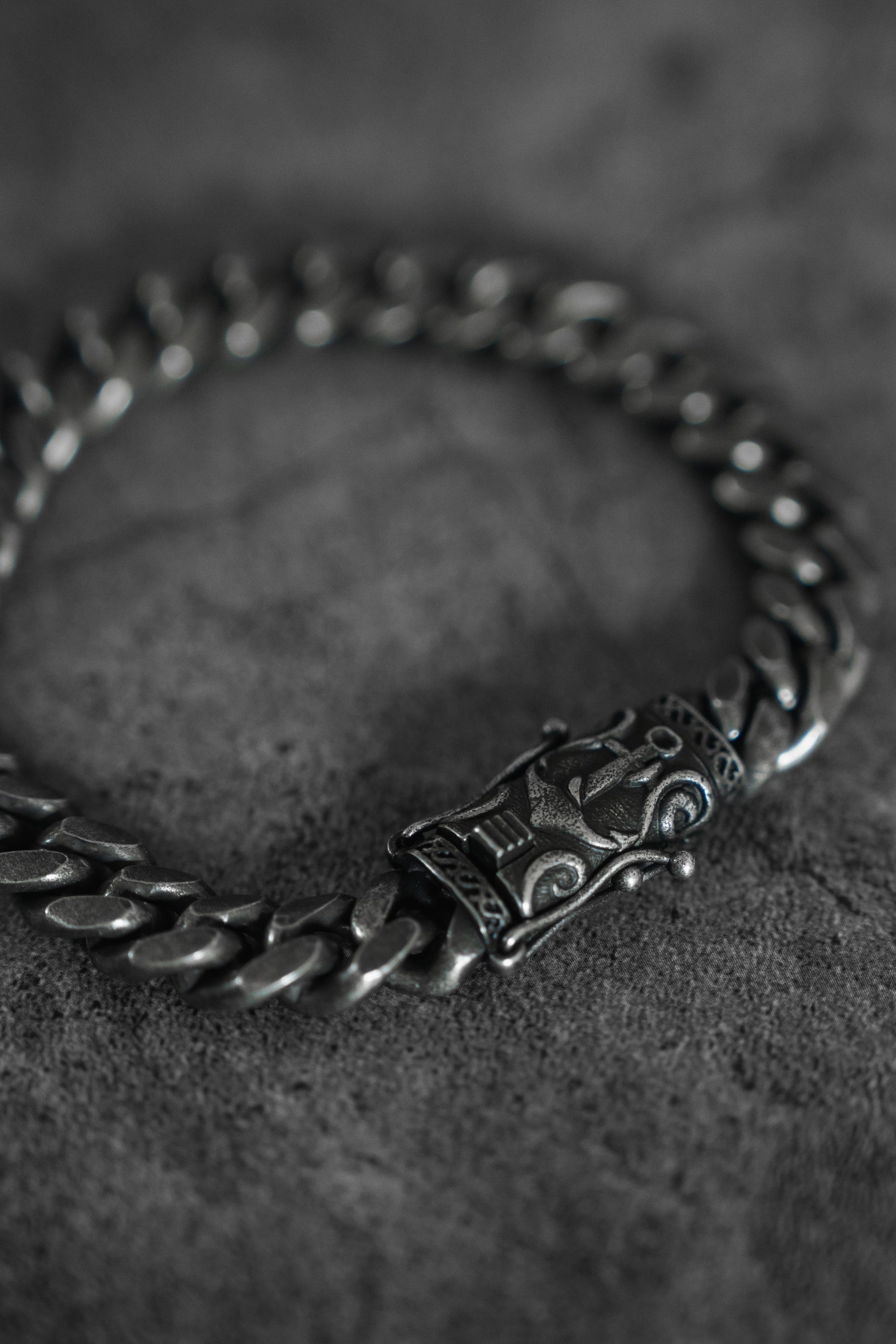 A detailed view of the Voyager Bracelet by Relentless Betrayal shows its intricate, handcrafted clasp against a textured dark gray background.