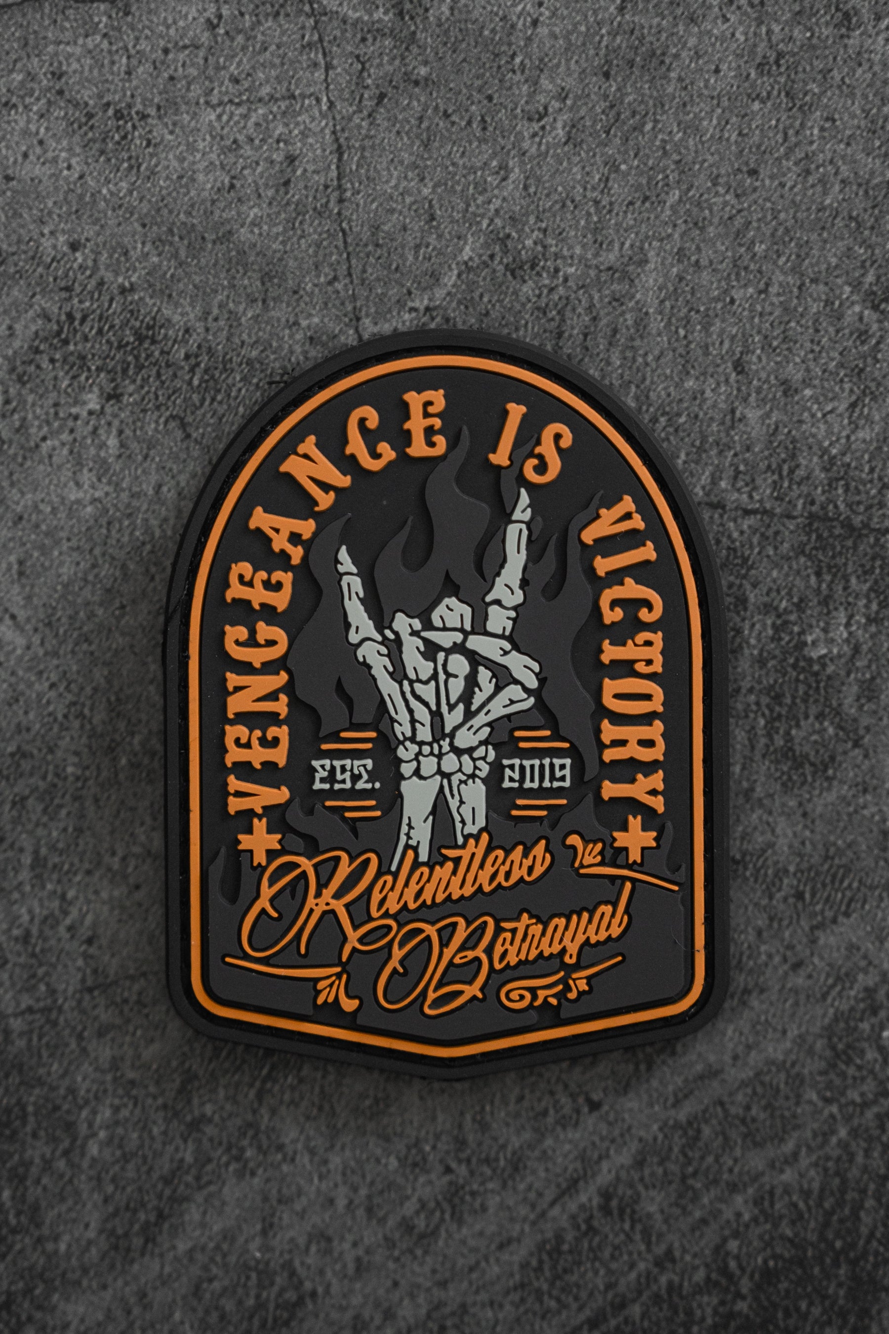 The Vengeance Patch by Relentless Betrayal showcases two clenched fists in flames with Vengeance is Victory above, and Relentless Betrayal 2919-3019 below. Set against a dark, textured background, it symbolizes resilience, personal growth, and fiery determination.