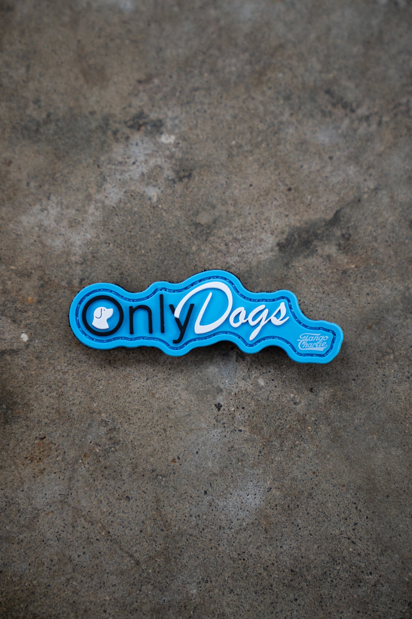 The Only Dogs PVC Patch by Tango Charlie Apparel features playful white and blue lettering with a small dog icon on blue, perfect for adding to concrete surfaces.