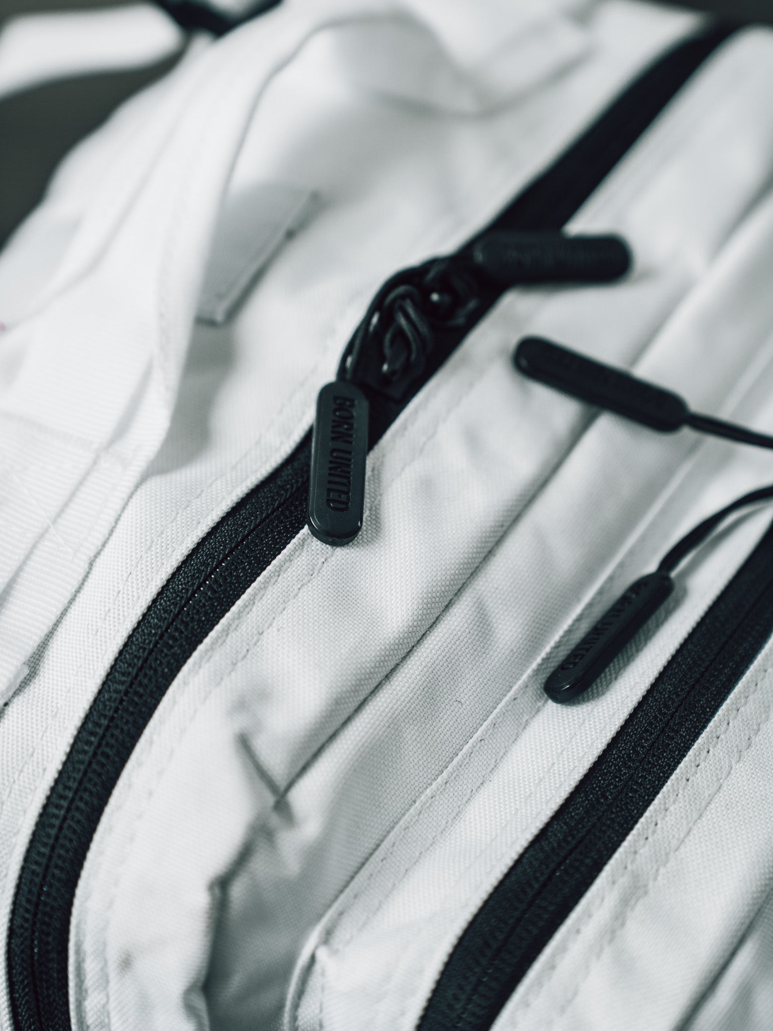 Close-up of the Born United Private Label Storm Trooper Tac-Pac - 45L, a white fabric bag with black zippers and pulls inspired by Stormtrooper armor, showcasing the detailed texture and quality hardware.