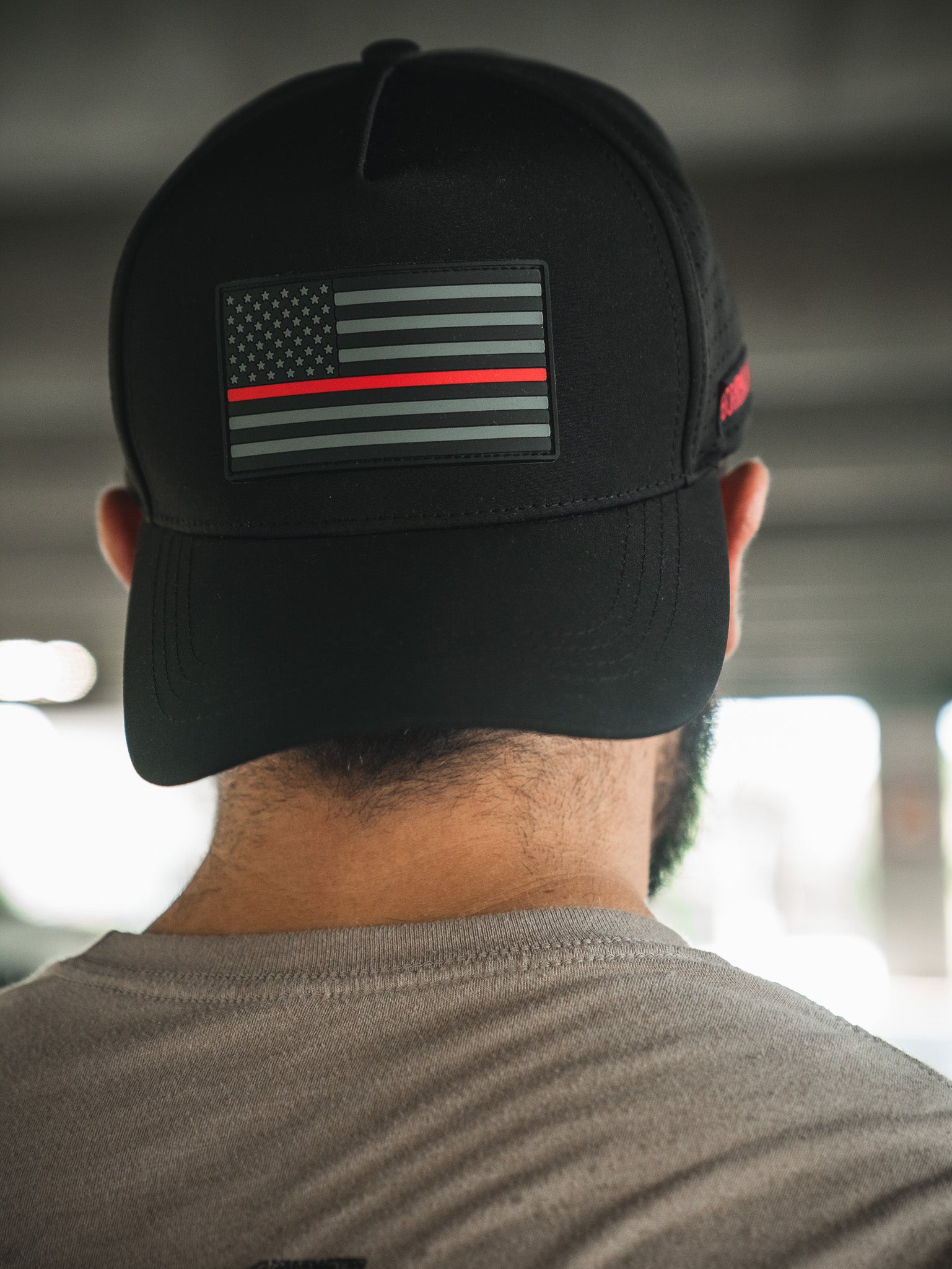 Someone is seen from behind wearing the Born United Premium Flag Snapback - TRL by Born United Private Label, a black cap featuring a monochrome American flag with a single red line on the back.