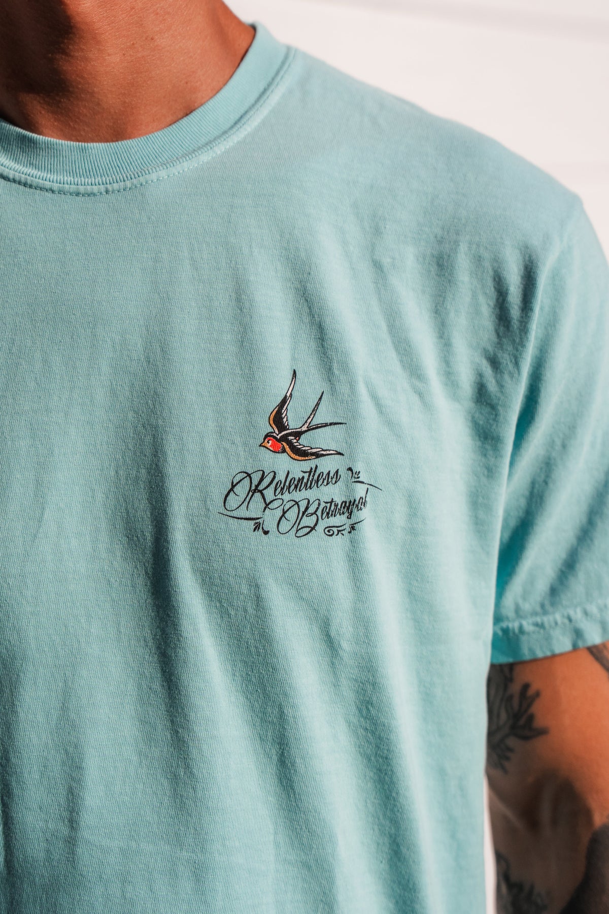 Wearing the To The Ends Of The Earth Premium T-Shirt by Relentless Betrayal—a light blue unisex premium tee featuring a small embroidered swallow and the words Relentless Bazaar on the chest. Made from 100% cotton, this comfortable shirt delivers both style and quality.