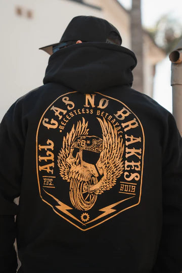 Wearing a black All Gas No Brakes Premium Hoodie by Relentless Betrayal, featuring a gold winged tire and slogan, this person epitomizes youth culture. Styled with a cap, the look is completed by the brands signature touch.