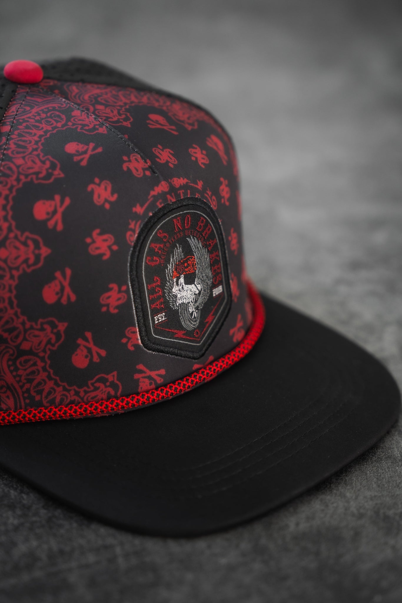 The All Gas No Brakes Premium Snapback by Relentless Betrayal showcases a fierce animal embroidered on the front, surrounded by intricate patterns reminiscent of a bandana print. The black and red cap is accented with red stitching and trim, enhancing its bold design.