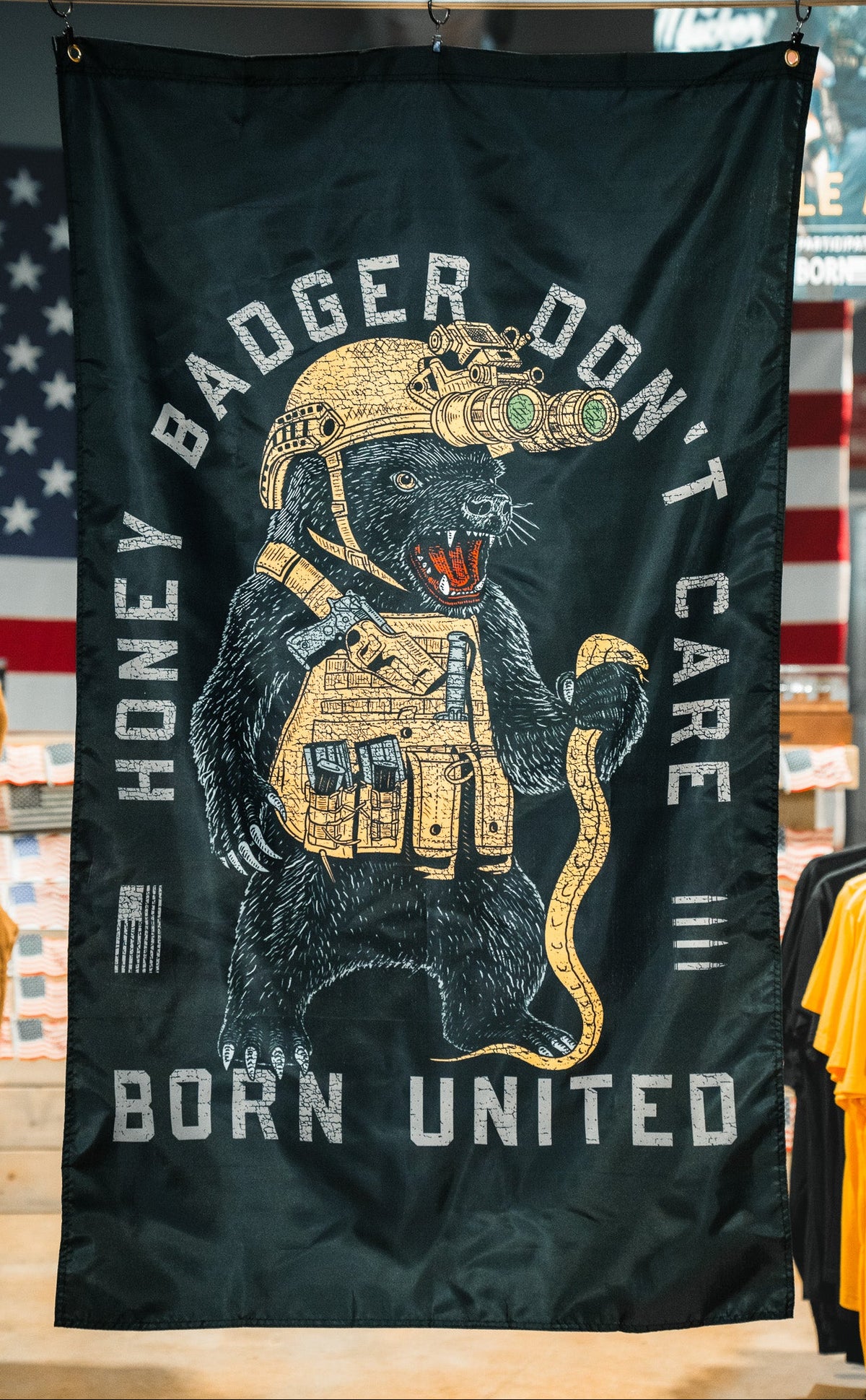 The Born United Private Label Honey Badgerin' Flag features a black banner with a bear in a helmet and yellow vest, crafted from durable polyester for lasting style.