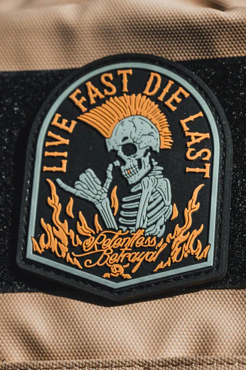The Live Fast Die Last PVC Patch by Relentless Betrayal features a skeleton with a mohawk, surrounded by flames and holding a playing card. The words LIVE FAST DIE LAST appear above and Relentless Betrayal is scripted below.
