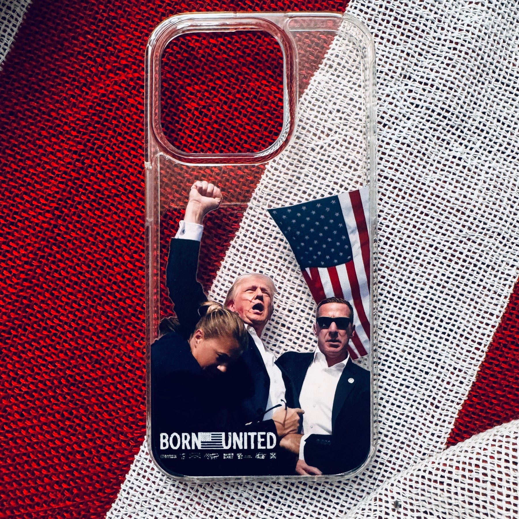 The Forever Legend iPhone Case by Born United Private Label showcases three people, an American flag, and BORN UNITED in white on a clear case over a red and white striped background—celebrating unity.