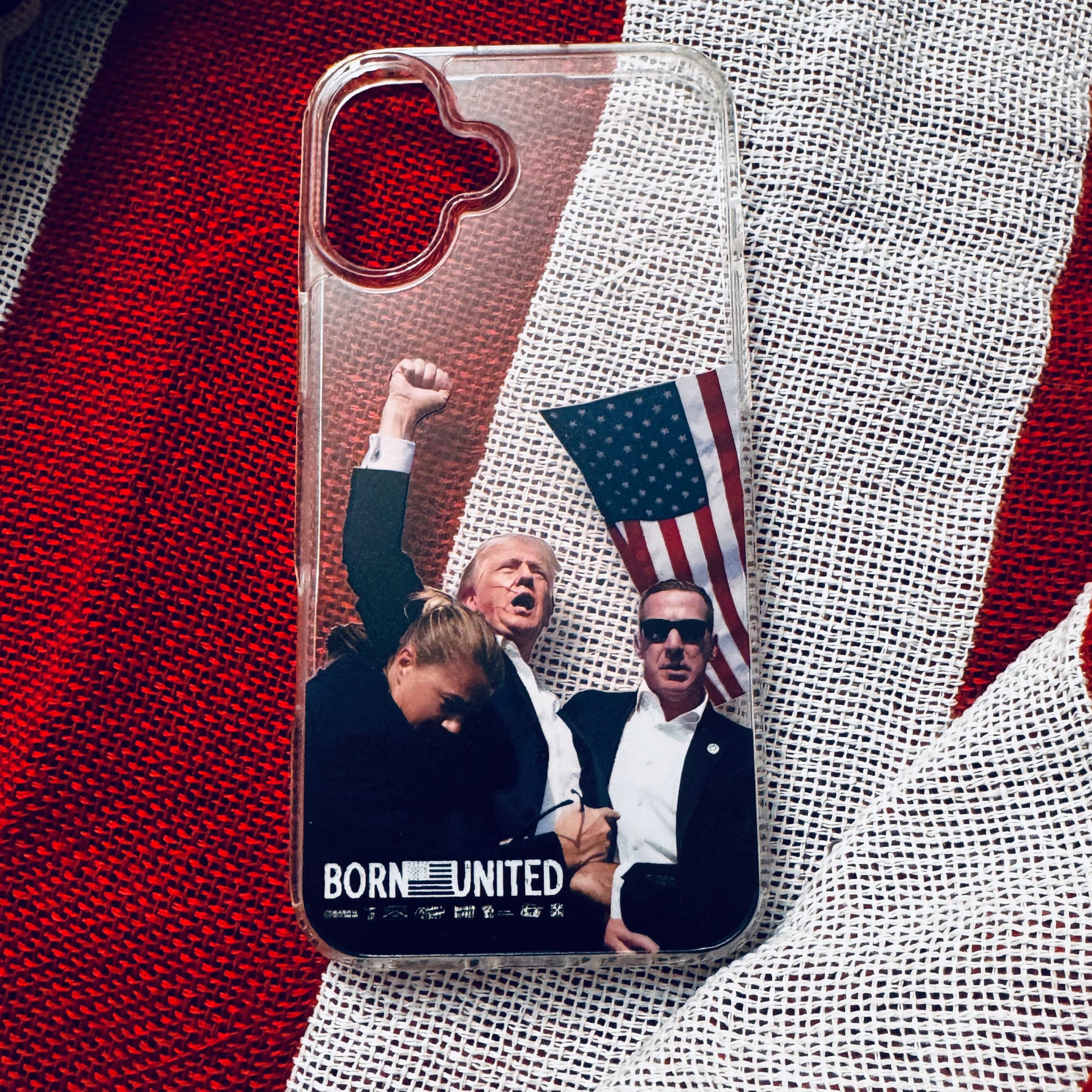 The Forever Legend iPhone Case by Born United Private Label features a collage of three figures—one raising a fist, another in sunglasses, with an American flag behind them and BORN UNITED at the bottom—all on a clear case.