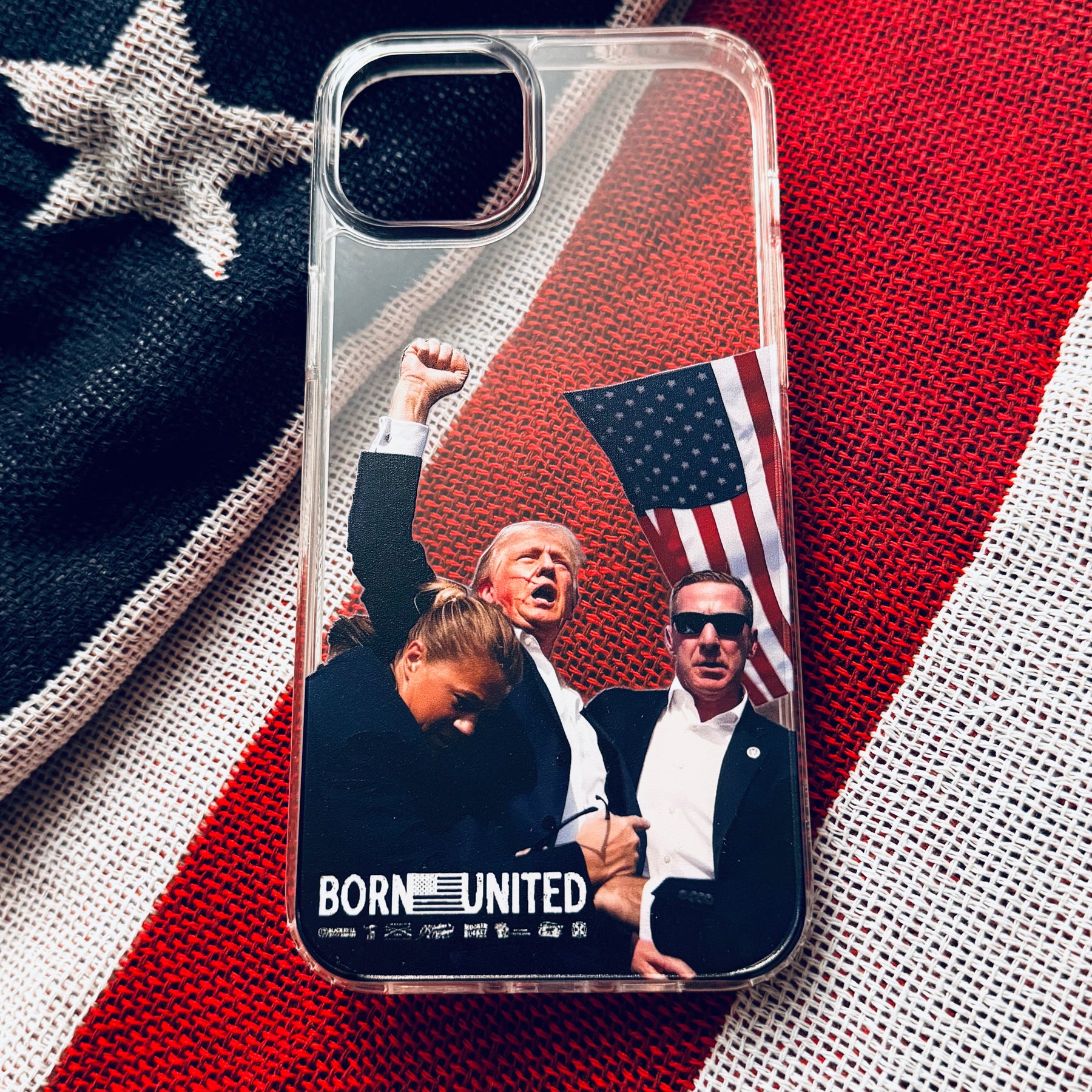 The Forever Legend iPhone Case by Born United Private Label features three figures—one raising a fist, another holding an American flag—and BORN UNITED at the bottom, all set on a textured American flag background.