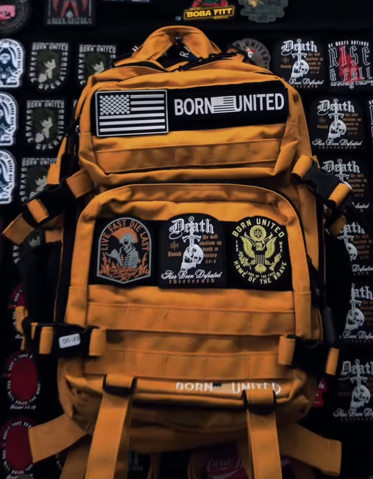 The Gold Glory Premium Tac-Pac - 45L from Born United Private Label features a golden yellow design with patches like the American flag and Born United, complemented by motifs such as Live Fast Die Last, capturing a spirit of glory amidst an array of unique designs.