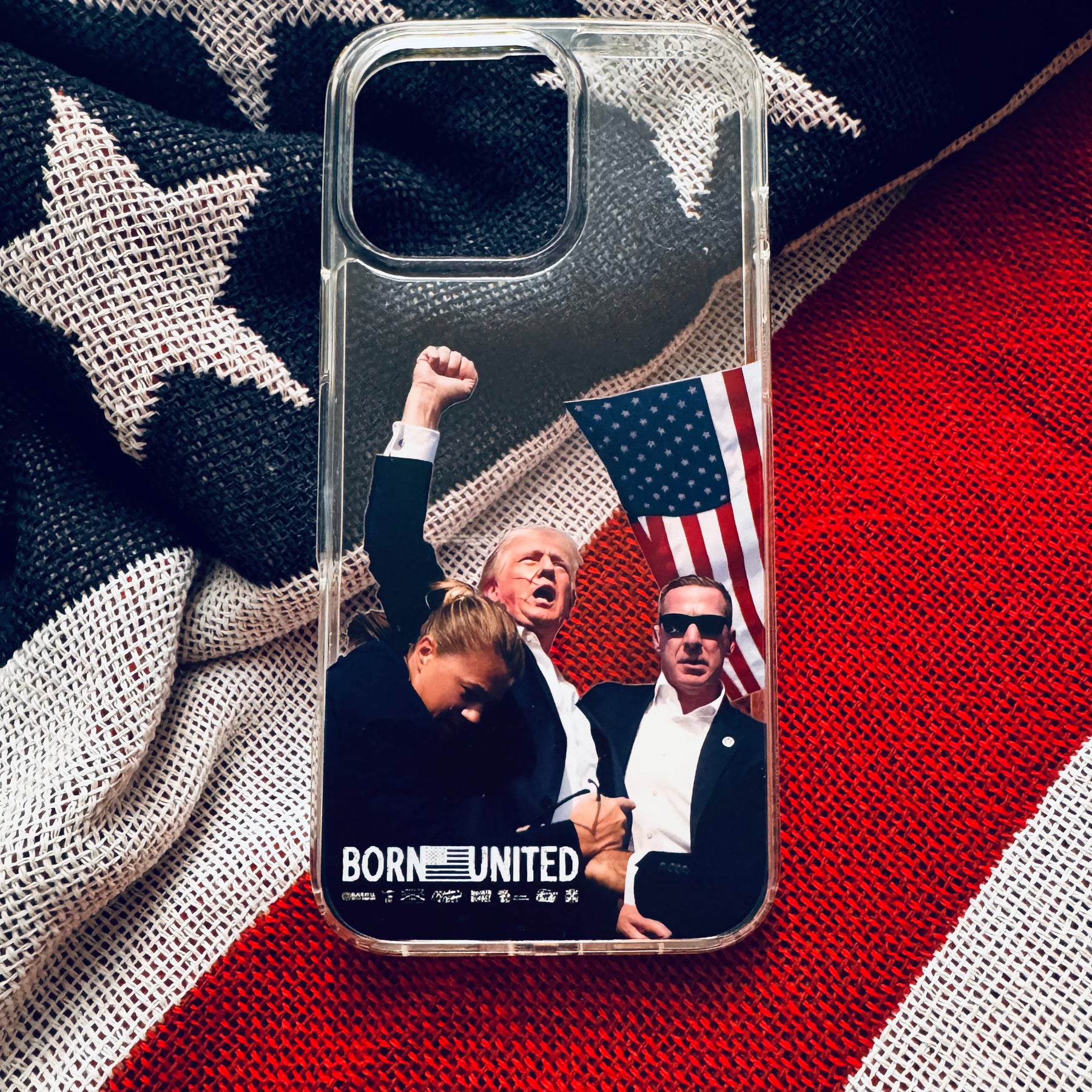 The Forever Legend iPhone Case by Born United Private Label features an American flag with three people—one raising a fist, another holding the flag—and BORN UNITED text plus symbols underneath, creating an iconic scene.