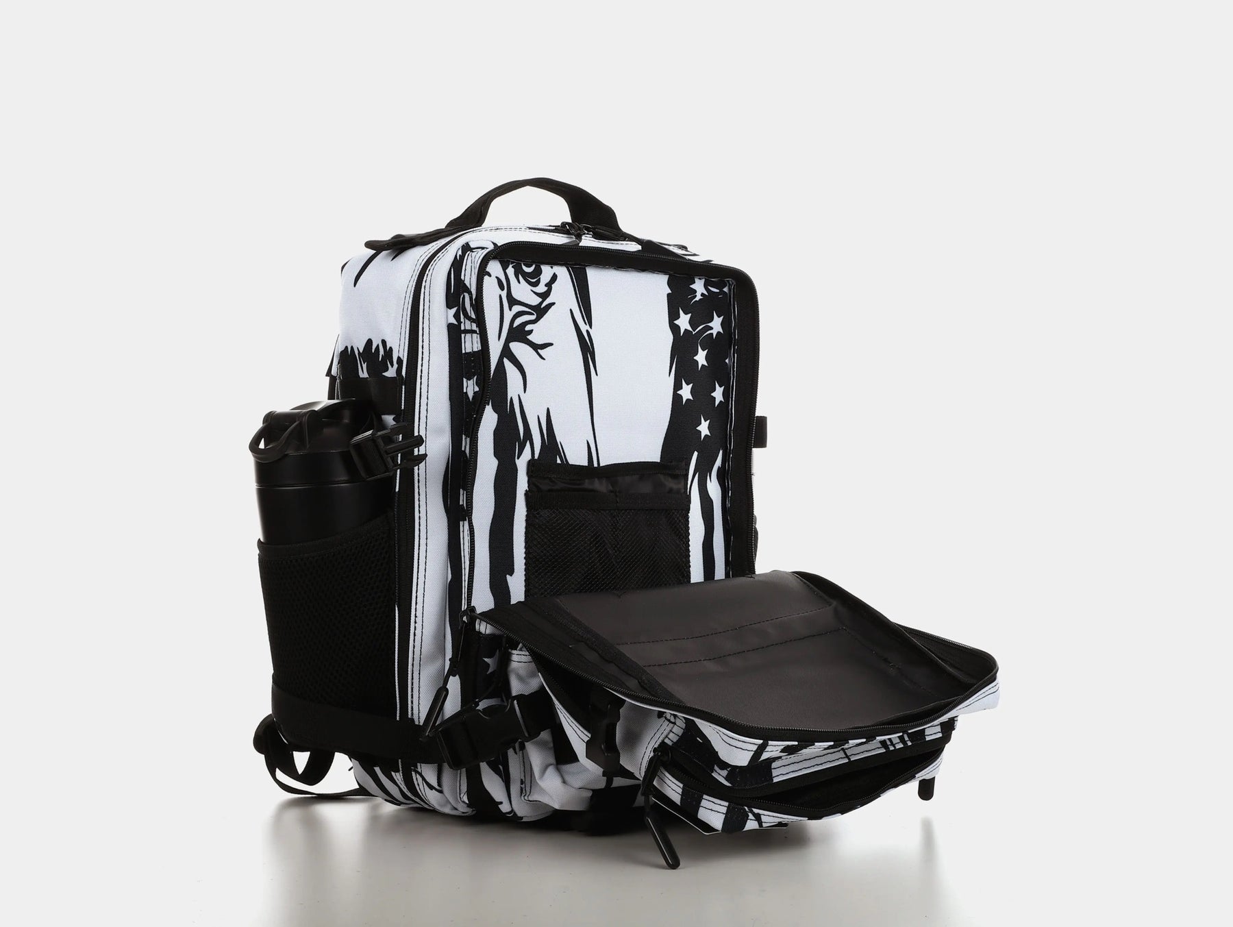 The American Stealth Special Edition Tac-Pac - 25L by Born United Private Label is a black and white backpack with graphic designs, featuring open compartments, side mesh pockets holding a black bottle, and an unzipped front flap revealing the interior against a plain white backdrop.