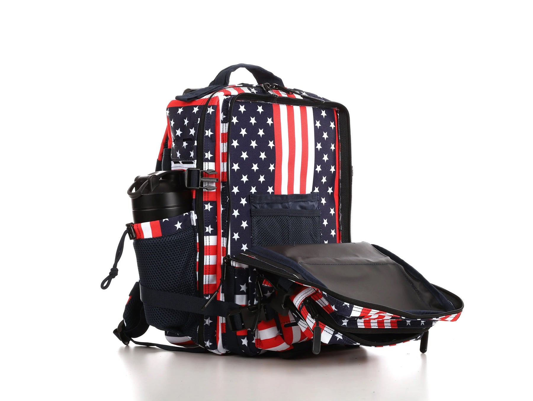 The Ultimate Patriot Special Edition Tac-Pac - 25L by Born United Private Label features an American flag design with red and white stripes and stars on blue. It has multiple compartments, including a side pocket with a black thermos, all showcased on a reflective white surface.