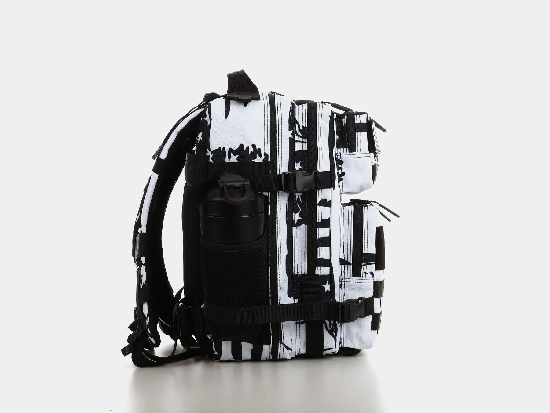 Side view of the American Stealth Special Edition Tac-Pac - 25L from Born United Private Label, showcasing a black and white pattern with a water bottle in a mesh pocket. The abstract design is inspired by stealth technology, set against a plain white background.
