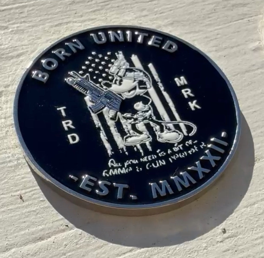 A collectible round coin from Born United Private Label features cartoon characters with weapons against an American flag. It includes the text All you need is a lot of ammo & gun in your face and has BORN UNITED TRD MRK on the edge.