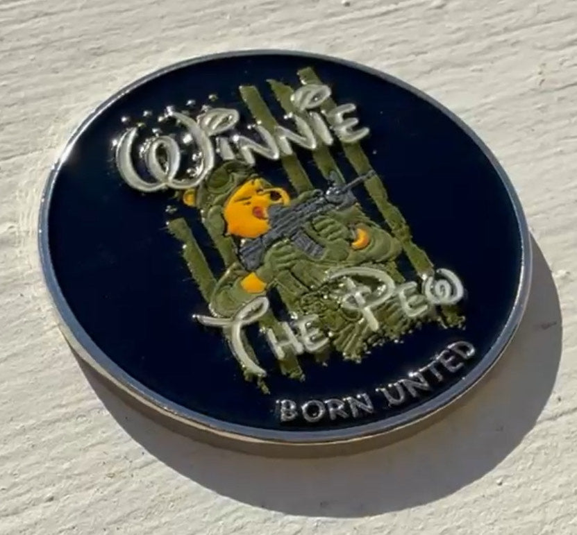 The Winnie The Pew challenge coin by Born United Private Label is a round metal piece featuring a bear in military gear with a rifle. It showcases the words Winnie The Pew and BORN UNITED, set against a light background that highlights its intricate craftsmanship.