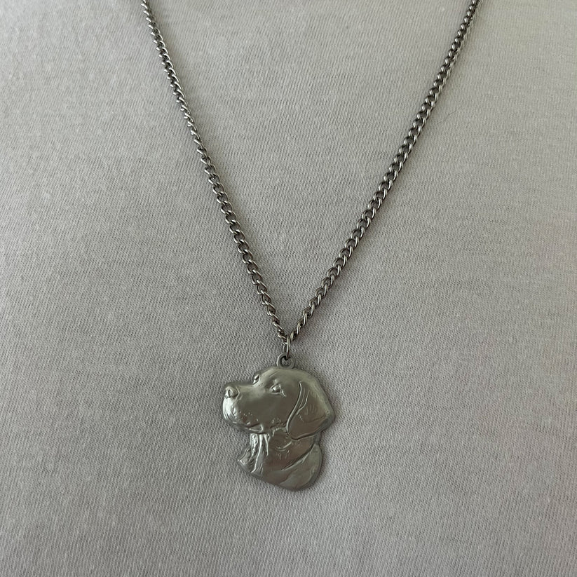 The Good Ol Boy stainless steel necklace by Mucker Bucket features a silver chain and a dog head pendant with detailed facial features and fur texture, displayed on a plain light gray background.