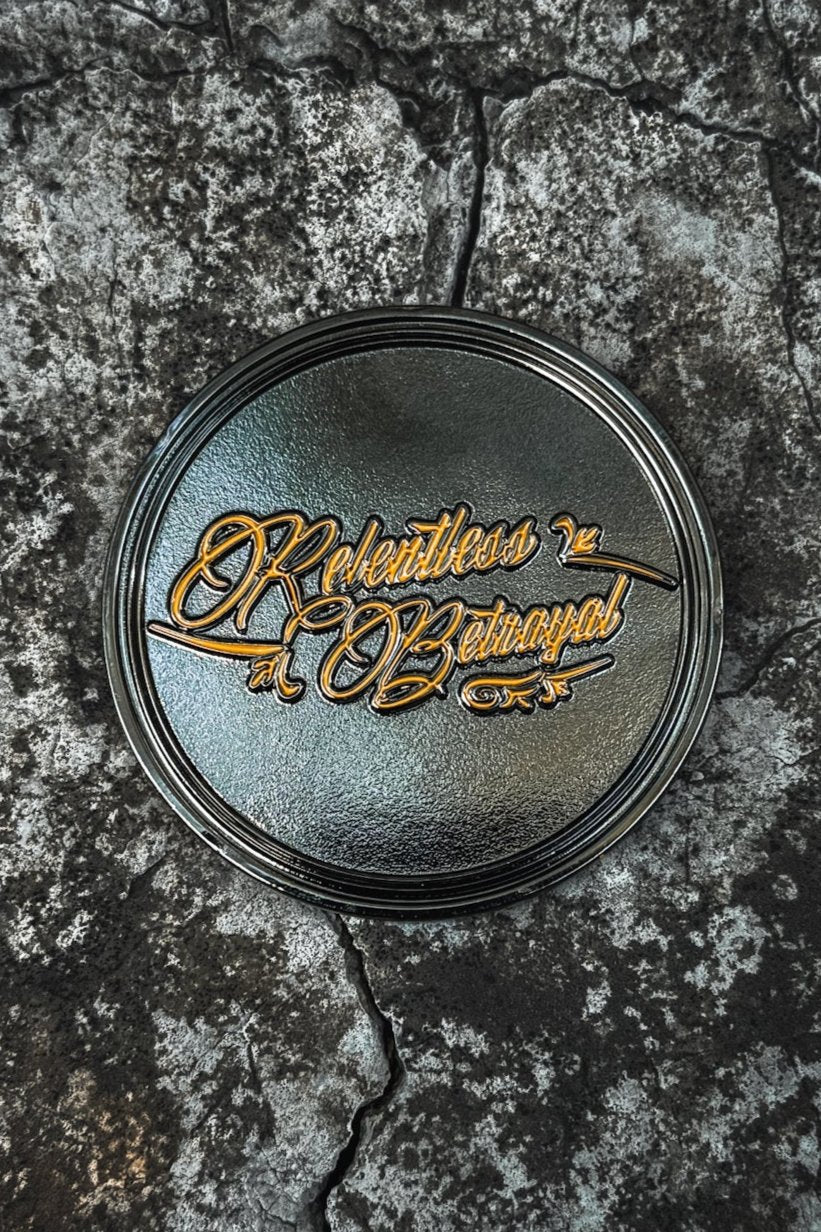 The Live Fast Die Last Challenge Coin by Relentless Betrayal is a handcrafted stainless steel round plate with Relentless Betrayal in ornate golden script over a cracked, stone-like dark background, evoking the allure of an ancient challenge coin.