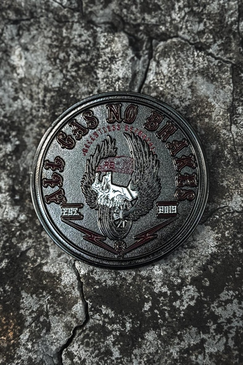 The All Gas No Brakes Challenge Coin by Relentless Betrayal features a stainless steel emblem of an eagle clutching a skull. The text ALL GAS NO BRAKES surrounds the bold design against a cracked, grunge stone backdrop, embodying relentless pursuit.