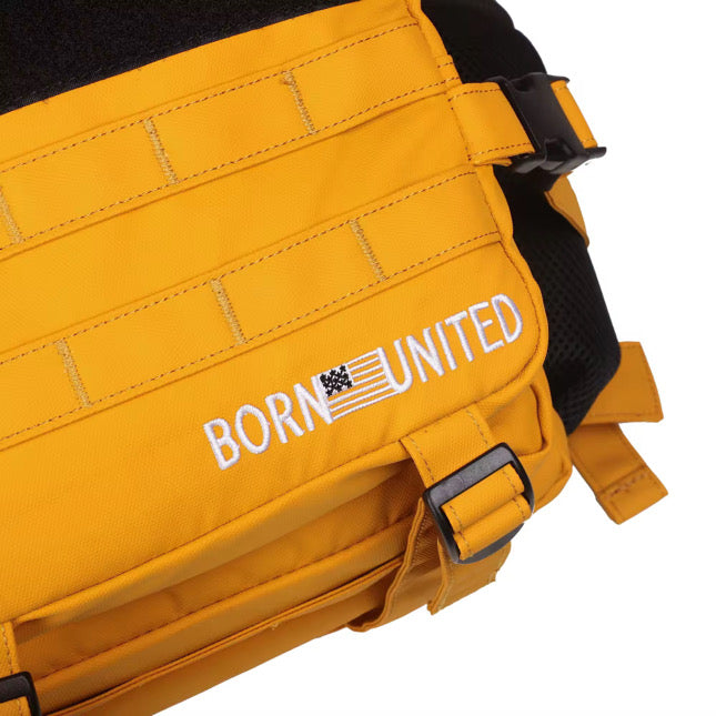 Close-up of the Gold Glory Premium Tac-Pac - 45L by Born United Private Label, showcasing the white BORN UNITED text and a flag design on a gold-hued bag. It has black straps and stitching details, exuding a sense of glory.