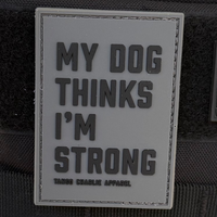 The My Dog Thinks Im Strong PVC patch by Tango Charlie Apparel is made from durable material, featuring a dark background.