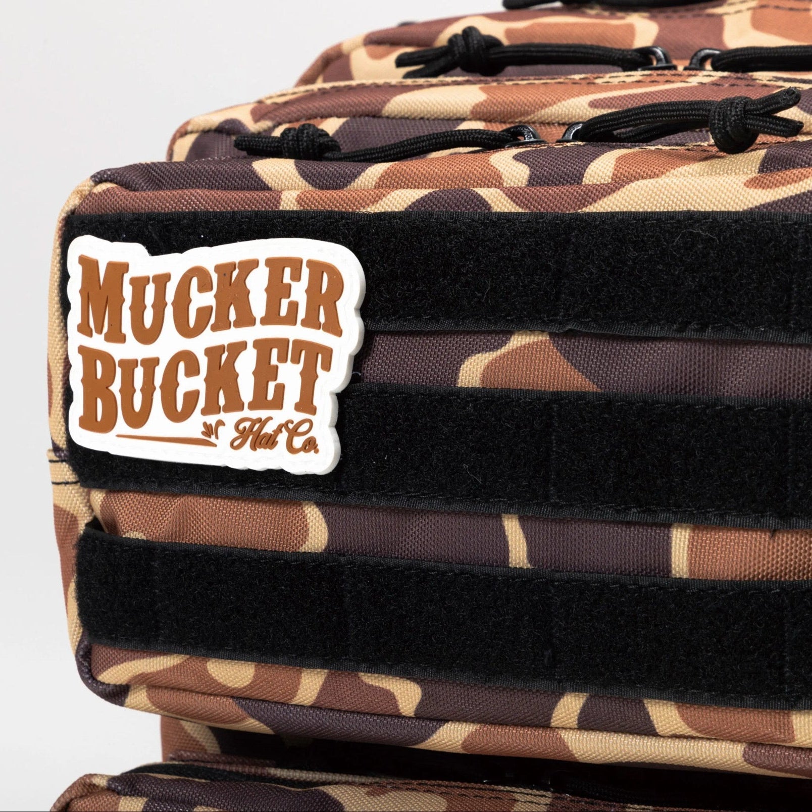 Close-up of the Mucker Bucket Duck It Limited Edition Tac-Pac 25L hunting backpack with black straps and a branded patch, perfect for your next adventure.