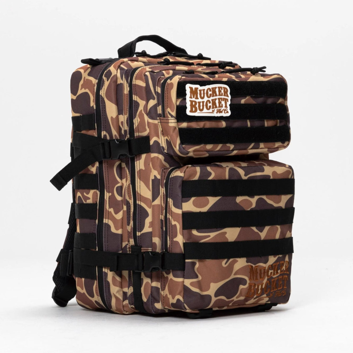 The Duck It Limited Edition Tac-Pac - 25L by Mucker Bucket is a camouflage-patterned hunting backpack with multiple compartments, black straps, and a Mucker Bucket patch on the top front pocket, shown against a plain white background.