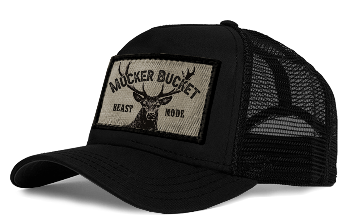 The Beast Mode OG Trucker Bucket features a black mesh-back with a fabric patch displaying a white tail deer and antlers, flanked by MUCKER BUCKET on top and BEAST MODE below.