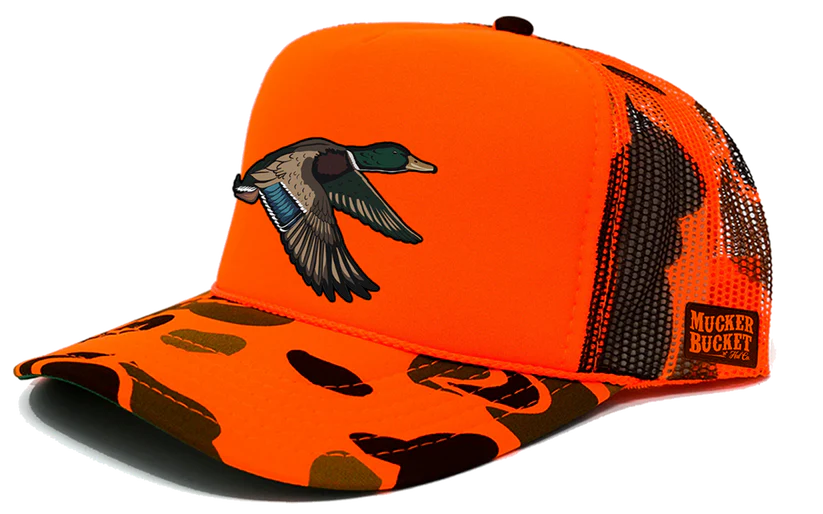 The Mucker Bucket Mallard Orange Camo Trucker features an orange cap, camo-patterned brim, and mesh back. A mallard embroidery adorns the front, with a Mucker Buck patch on the side.