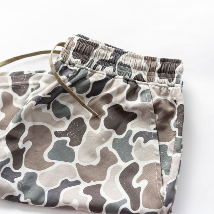 The Mens Performance Athletic Shorts | 5.5- Duck It by Mucker Bucket feature a duck-themed camouflage in beige and gray, with an elastic waistband and drawstring, shown flat on a white background.