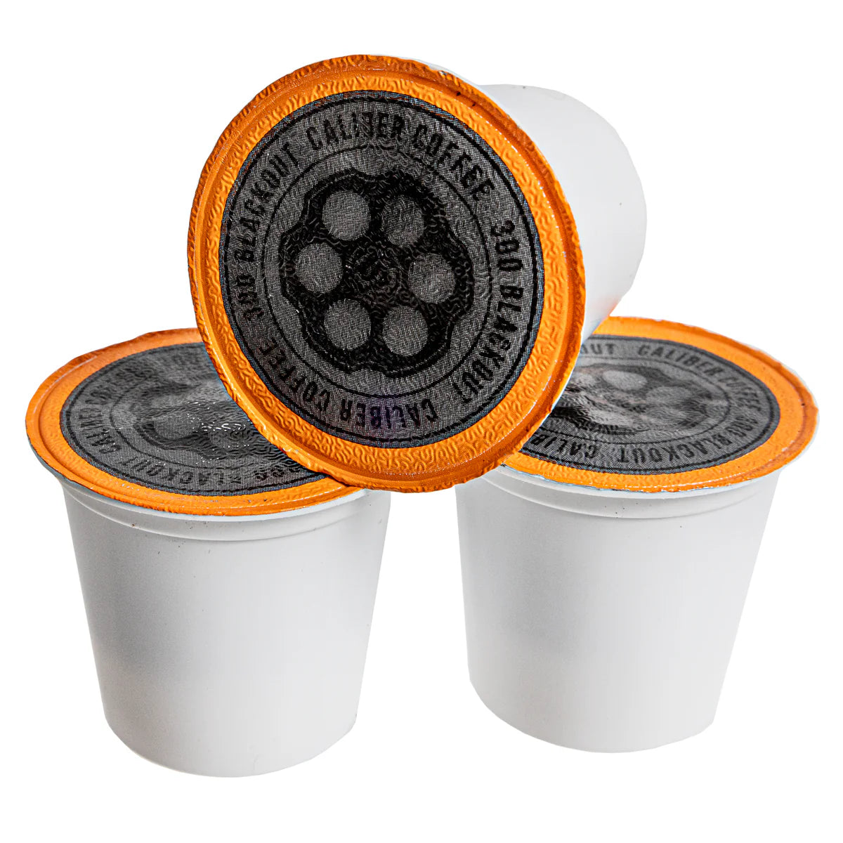 Three Caliber Coffee Company Dark Roast 300 Blackout Single-Serve Shells, white with orange rims and black circular labels featuring bean designs, are stacked in a trio: two in front with one balancing on top. Specialty grade and single-origin coffee awaits inside.