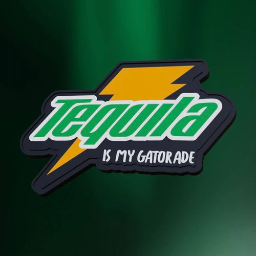 The Tequila Is My Gatorade Patch by Tango Charlie Apparel features a digital graphic with Tequila in bold green and white, separated by a yellow lightning bolt on a dark green blurred background. Designed as a PVC patch, it includes adhesive backing for easy application on any surface.