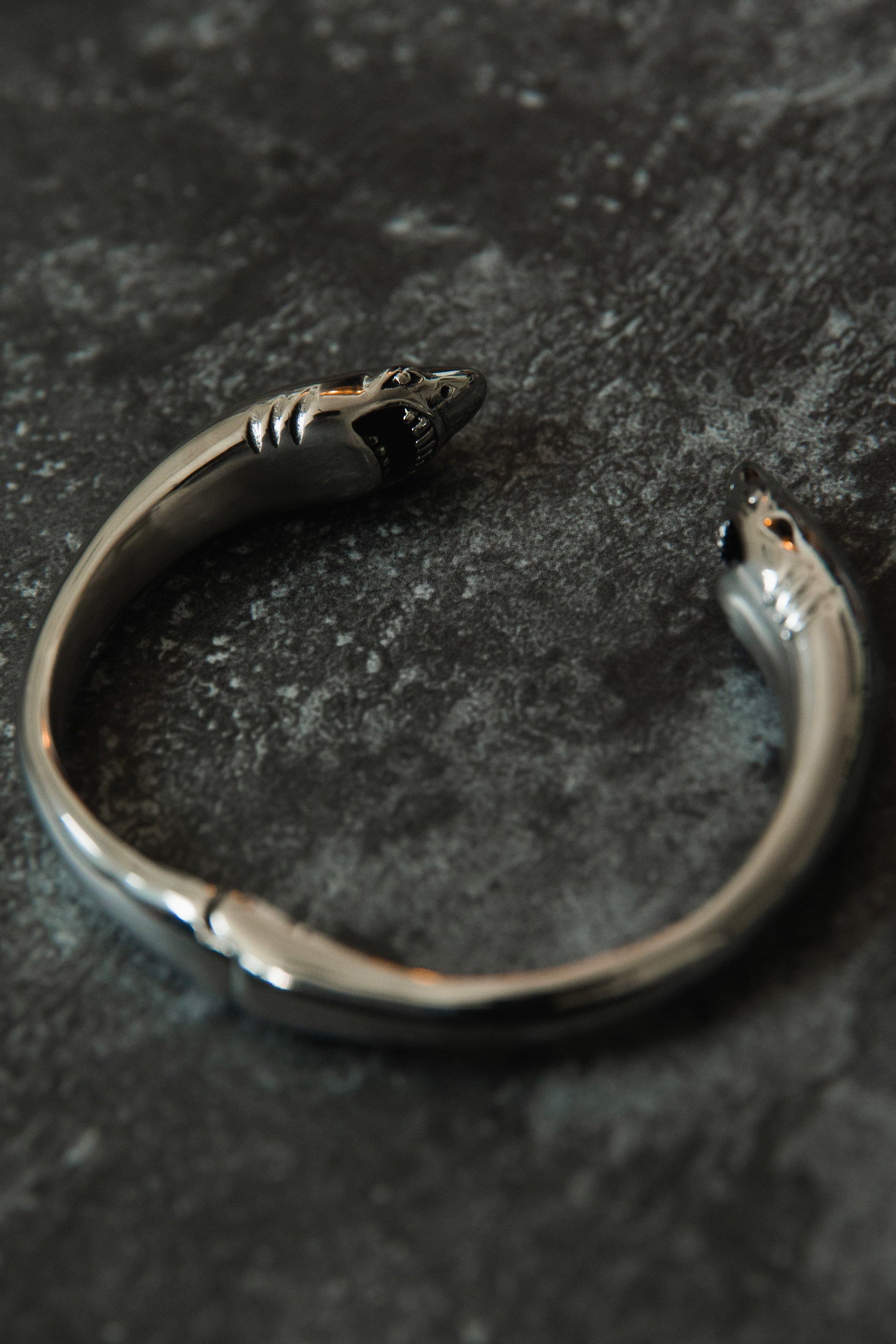 Explore the Shark Bait Bracelet by Relentless Betrayal: a bold silver cuff with snake head accents, textured dark surface, crafted from durable stainless steel. This piece includes a lifetime warranty for enduring elegance and assurance.