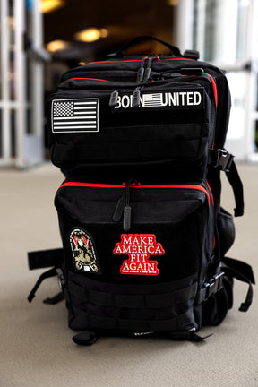 The Black Widow Premium Tac-Pac - 45L by Born United Private Label, featuring an American flag patch, "Born United" text, "Make America Fit Again" patch, and another embroidered patch, sits indoors on a light floor with durable MOLLE webbing for gear.