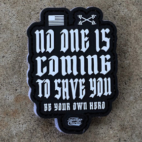 The Tango Charlie Apparel "No One Is Coming To Save You - Patch" is a 3" black and white 3D PVC patch with flag and crossed barbells icons, Velcro backing, and reads: No one is coming to save you. Be your own hero.