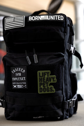 The Born United Private Label Midnight Black Premium Tac-Pac - 45L features patches reading BORN UNITED, an American flag, TRAINED FOR VIOLENCE, and LIFT HEAVY. PET DOGS., plus multi-compartment storage and durable zippers.