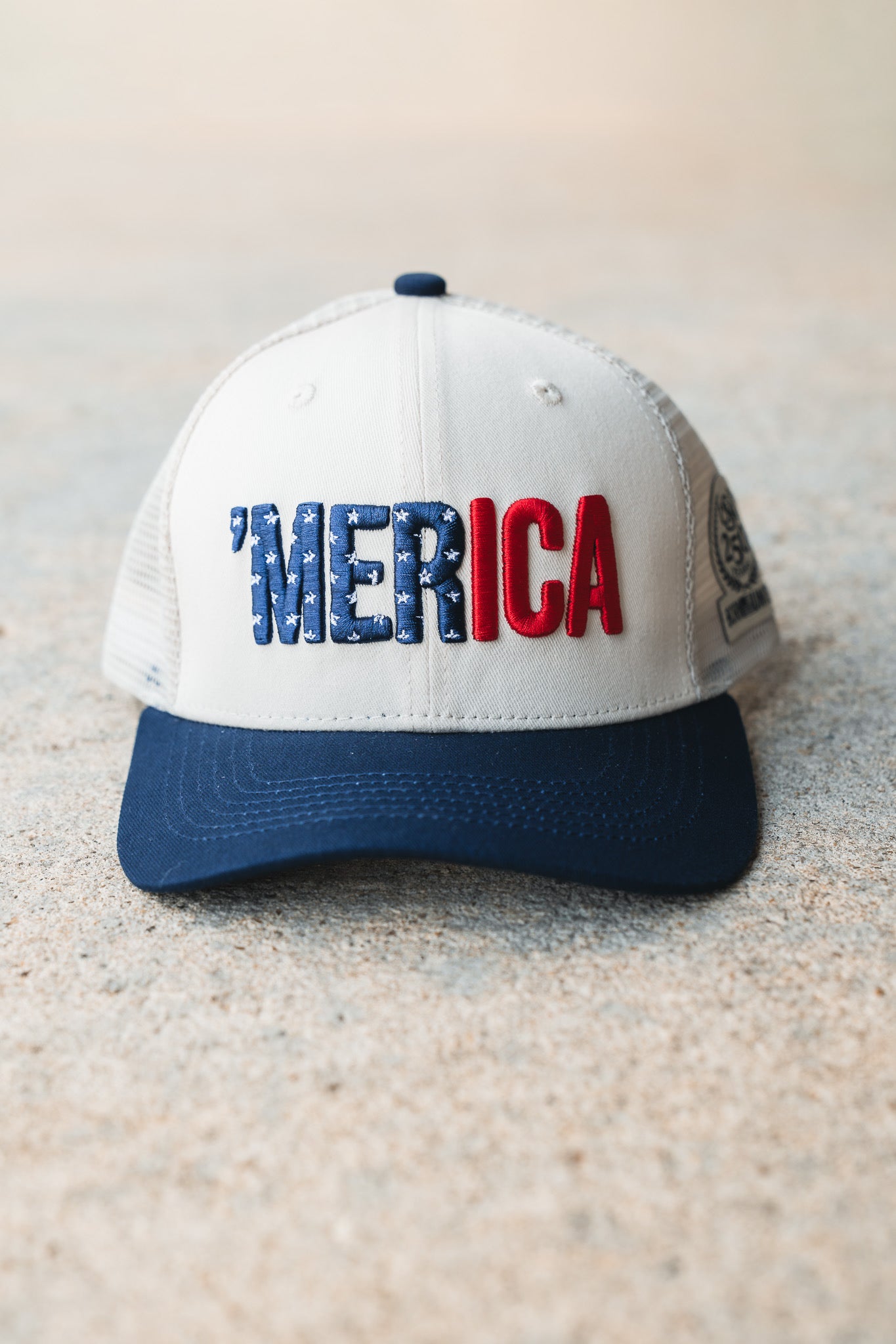 The Born United Private Label ’Merica Trucker Snapback is a white and blue trucker hat featuring “MERICA” embroidered on the front in blue stars and red letters. This breathable snapback blends classic style with all-day comfort.