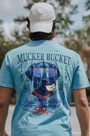 Person wearing a blue 'Mucker Bucket' t-shirt with a graphic of a dog and text.
