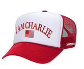 The I Am Charlie Red Trucker Snapback by Born United Private Label features a red and white flat bill, "I AM CHARLIE" in red above a small American flag, a breathable red mesh snapback, and "BORN UNITED" in white on the side.